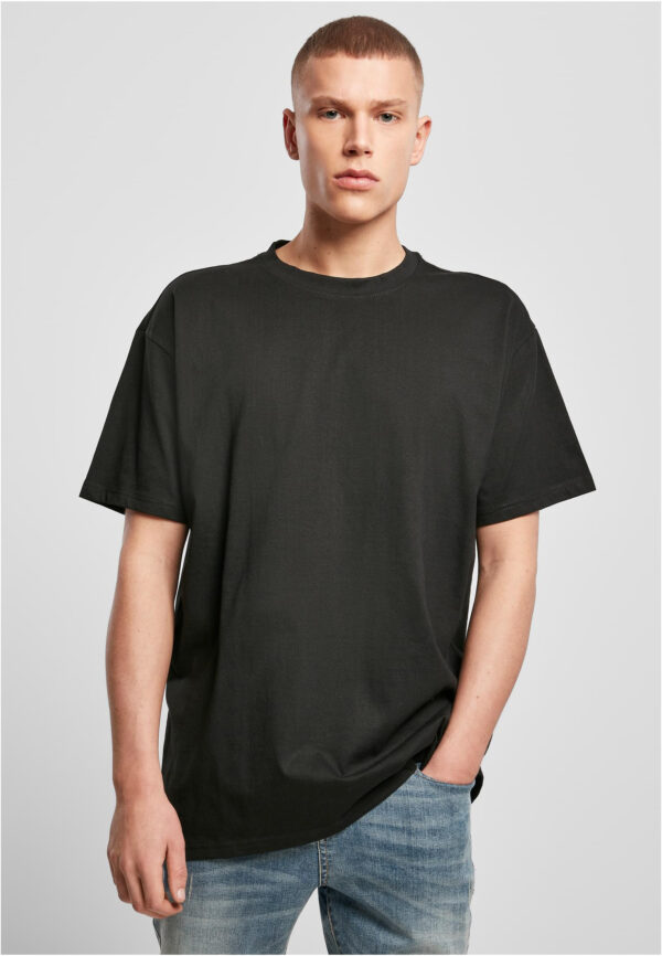 Model trägt ein schwarzes Build Your Brand BY102 Heavy Oversize T-Shirt mit überschnittenen Schultern und Jeans.